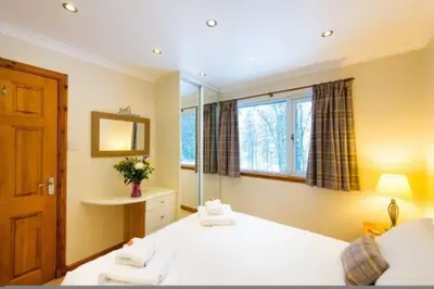 a bedroom with a large bed and a window at Osprey Lodge with river and mountain view in Crianlarich