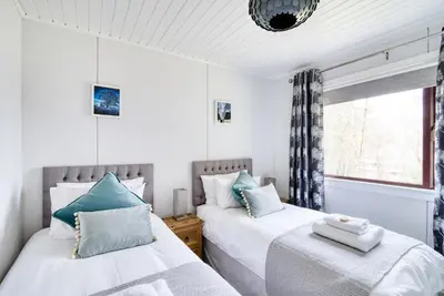 two beds in a room with a window at Otter with mountain view and enclosed decking in Crianlarich