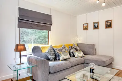a living room with a couch and a table at Otter with mountain view and enclosed decking in Crianlarich