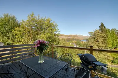 a table with a vase of flowers on a balcony at Stunning 5 star lodge with loch and mountain views in Crianlarich