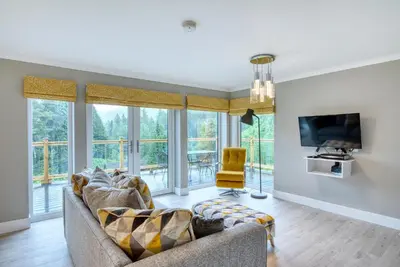 a living room with a couch and a tv at Stunning 5 star lodge with loch and mountain views in Crianlarich