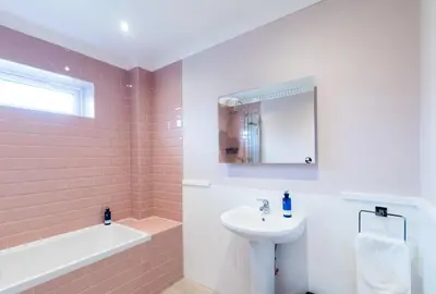 a white bathroom with a sink and a bath tub at Stunning 5 star lodge with loch and mountain views in Crianlarich