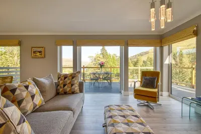 a living room with a couch and a table at Stunning 5 star lodge with loch and mountain views in Crianlarich