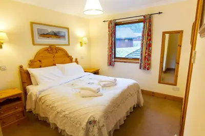 a bedroom with a large bed and a mirror at Raven Lodge with beautiful views of Loch Dochart in Crianlarich