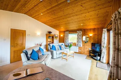 a living room with a couch and a tv at Raven Lodge with beautiful views of Loch Dochart in Crianlarich