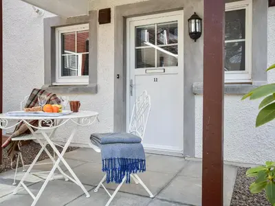 a table and chair on a patio with a white door at Can Duran in Killin