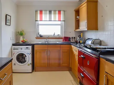 a kitchen with a sink and a washing machine at The Potting Shed in Challoch