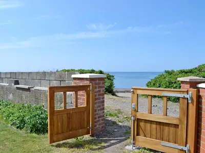 two wooden gates and a brick wall and the ocean at Ingleside in Ballantrae