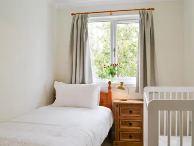 a small bedroom with a bed and a window at Invernoe Cottage in Taynuilt