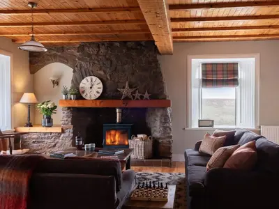 a living room with a stone wall and a fireplace at High Ranachan in Campbeltown