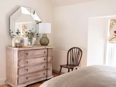 a bedroom with a dresser with a mirror and a chair at High Ranachan in Campbeltown