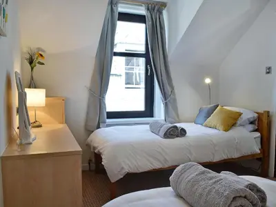 a bedroom with two beds and a window at Summerlea Cottage in Moffat