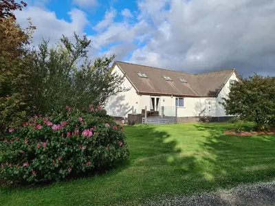 a house with a yard with pink flowers at Coel Ila in Benderloch