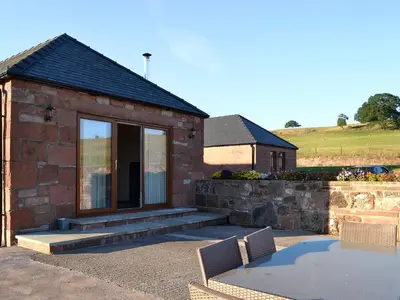 a small brick house with a table and chairs at Liftingstane Dairy Cottage in Closeburn