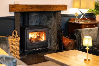 a fireplace in a living room with two chairs and a table at Altskeith Country House in Aberfoyle