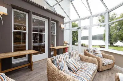 a conservatory with couches and a table and windows at Altskeith Country House in Aberfoyle