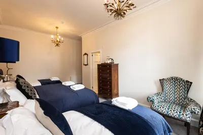 a bedroom with two beds and a chair at Altskeith Country House in Aberfoyle