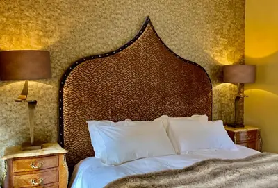a bedroom with a bed with a large headboard and two lamps at Altskeith Country House in Aberfoyle