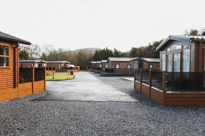 a row of houses on a gravel road with a fence at Atlas Ovation Lodge in Auchterarder