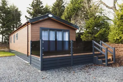 a tiny house with a porch and a staircase at Atlas Ovation Lodge in Auchterarder