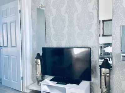 a flat screen tv sitting on a white stand in a room at DUNOON - TOWN CENTRE HOLIDAY HOME APARTMENT in Dunoon