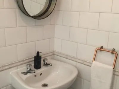 a white bathroom with a sink and a mirror at The Clacks Rustic Abode in Tillicoultry