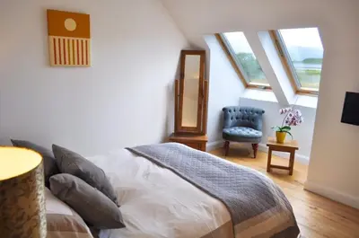 a bedroom with a bed and a chair and windows at Lurach House in Port Appin