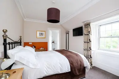 a bedroom with a large bed and a window at Mansewood Country House in Lochearnhead