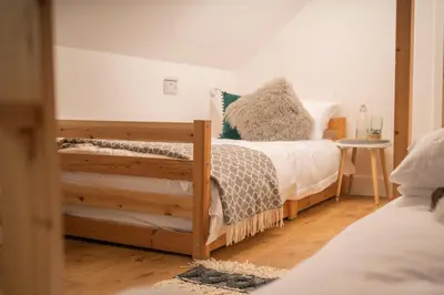 a bedroom with two beds and a wooden floor at Forty Winks Loch Lomond in Balloch