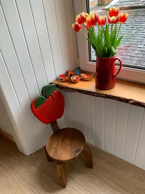 a vase of tulips sitting on a window sill next to a wooden chair at Cameron Cottage in Inverkip