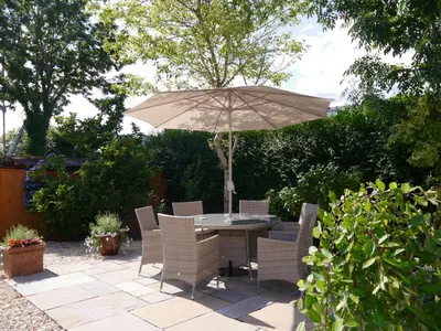 a table and chairs with an umbrella on a patio at Cameron Cottage in Inverkip