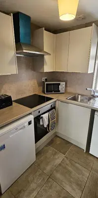 a kitchen with white cabinets and a sink at Balmaha Lodges and Apartments in Balmaha