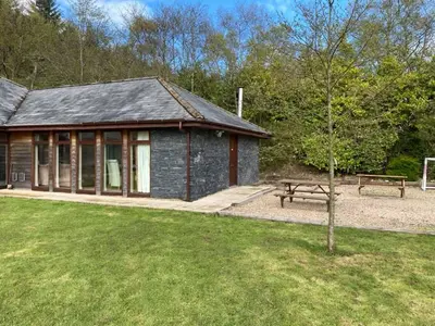 a building with a picnic table and a bench at Balmaha Lodges and Apartments in Balmaha