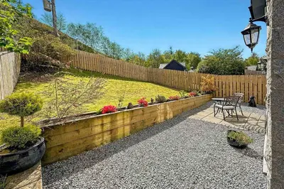 a garden with a wooden fence and a table and chairs at Outlander Glencoe at Creag an-t Sionnaich Glencoe Ballachulish Highlands Near Fort William in Glencoe