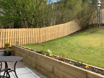 a fence with a table and chairs in a backyard at Outlander Glencoe at Creag an-t Sionnaich Glencoe Ballachulish Highlands Near Fort William in Glencoe