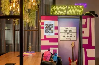 a table with a sign on a wall with a guitar at Moxy Glasgow Merchant City in Glasgow