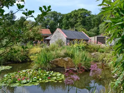 a garden with a pond with flowers and a building at Wee Cordorcan - Uk5890 in Bargrennan