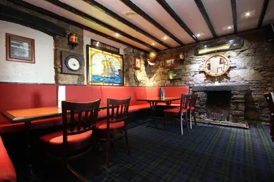 a bar with tables and chairs and a stone wall at The Anchorage in Troon