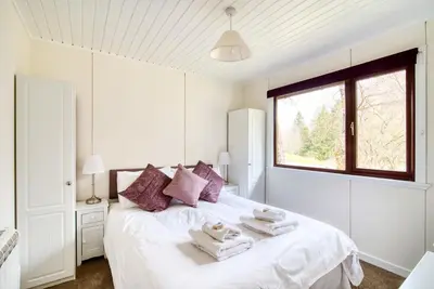 a white bedroom with a bed with towels on it at 2 bedroom lodge with free WiFi and mountain view in Crianlarich