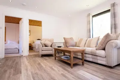 a living room with a couch and a table at 2 bedroom lodge with free WiFi and mountain view in Crianlarich