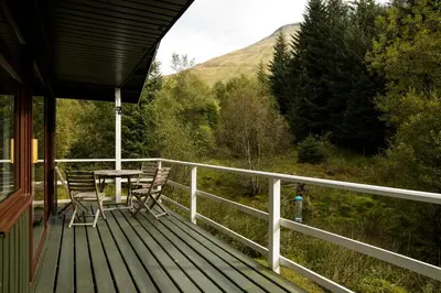 a wooden deck with a table and chairs on it at 2 bedroom lodge with free WiFi and mountain view in Crianlarich
