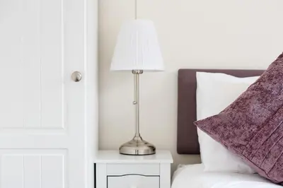 a lamp on a night stand next to a bed at 2 bedroom lodge with free WiFi and mountain view in Crianlarich