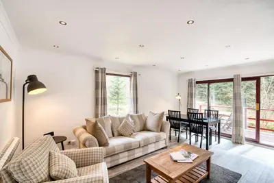 a living room with a couch and a table at 2 bedroom lodge with free WiFi and mountain view in Crianlarich