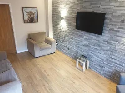 a living room with a tv on a brick wall at Oldwood Place Townhouse in Livingston