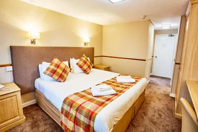 a hotel room with a bed with two towels on it at Abbotsford Hotel in Dumbarton