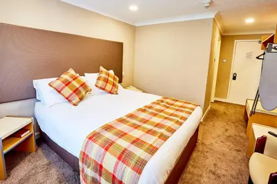 a hotel room with a large white bed with pillows at Abbotsford Hotel in Dumbarton