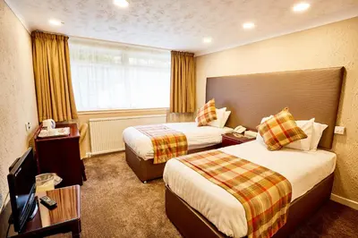 a hotel room with two beds and a television at Abbotsford Hotel in Dumbarton