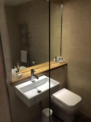 a bathroom with a sink and a toilet and a mirror at Abbotsford Hotel in Dumbarton