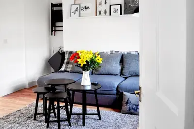 a living room with a blue couch and a table with flowers at Stylish Flat in 1860's Listed Building in Edinburgh