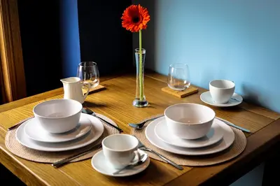a wooden table with plates and cups and a vase with a flower at Bay and Bridge near Edinburgh in Dunfermline